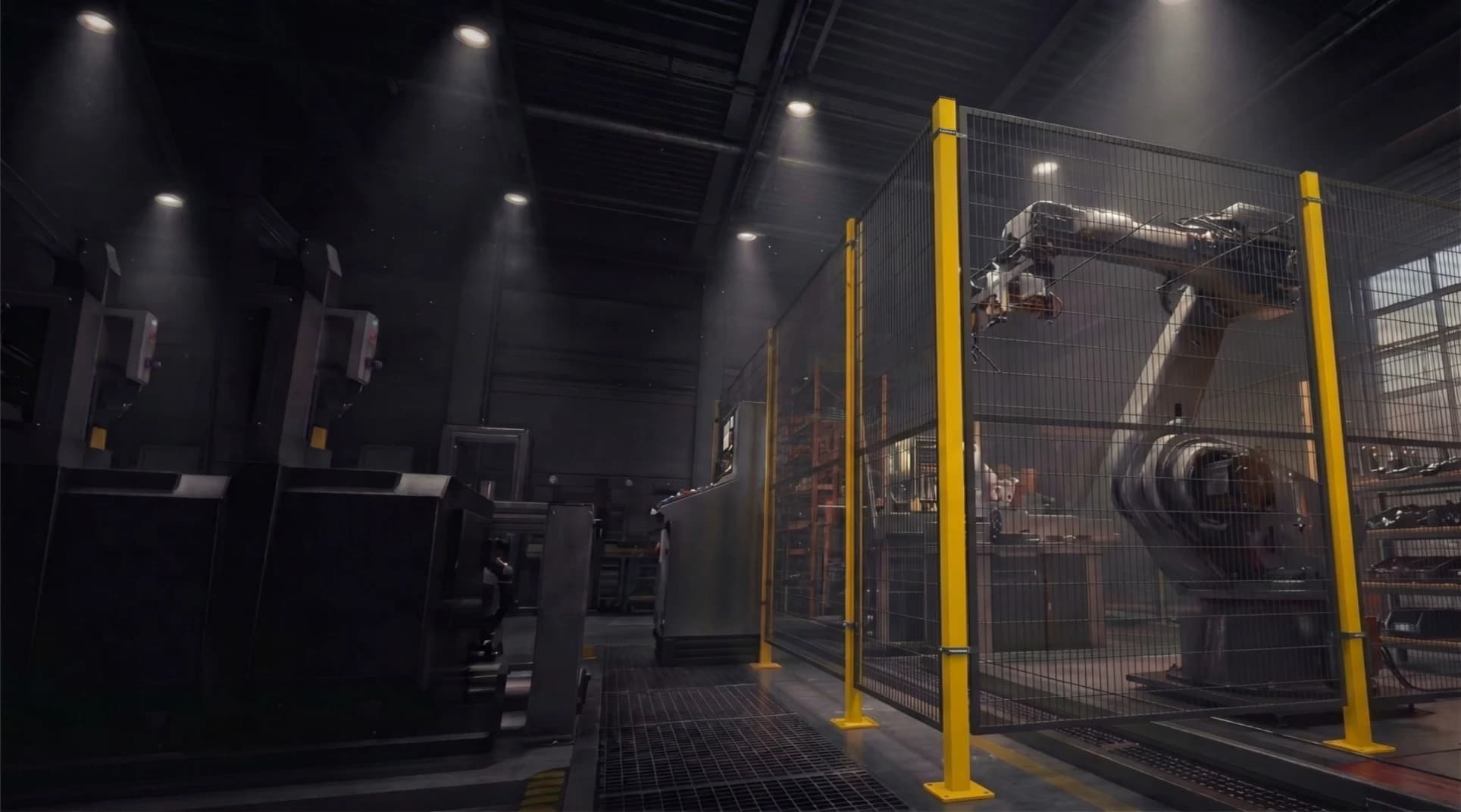 Yellow-framed black wire-mesh machine guarding enclosing an industrial robot arm inside a dark factory hall
